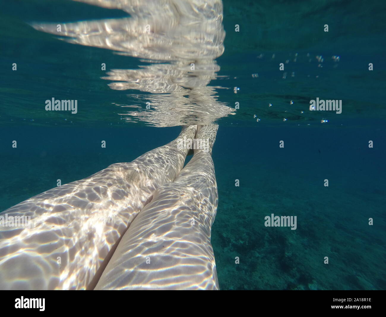 Closeup schoss der Beine der Frau unter dem Meer gegen den klaren grünen Hintergrund Stockfoto