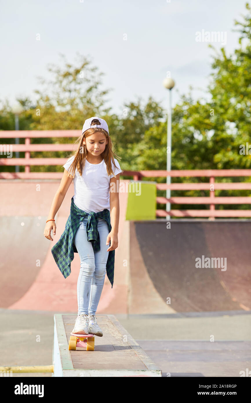 Mädchen in Freizeitkleidung auf Skateboard und lernen Sie in der skateboard Park im Freien zu reiten Stockfoto