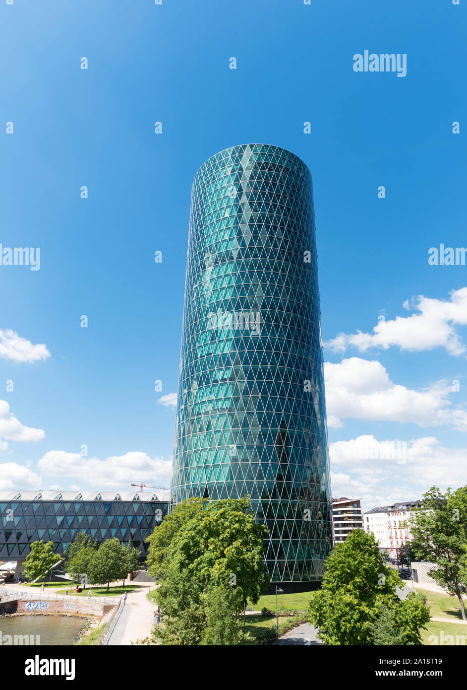 Der Westhafen Tower in Frankfurt am Main mit Bäumen in der Front an einem bewölkten Tag Stockfoto