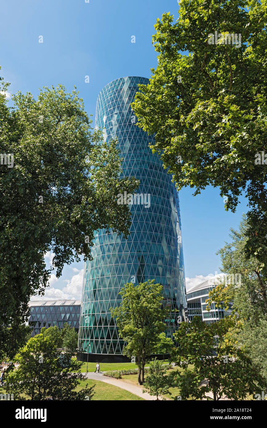 Der Westhafen Tower in Frankfurt am Main mit Bäumen in der Front an einem bewölkten Tag Stockfoto