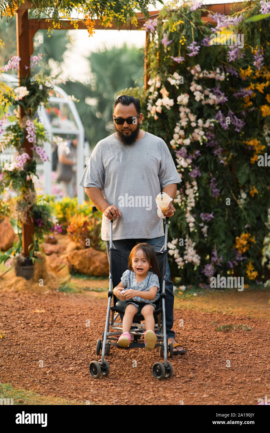 Asiatische Vater mit Kind im Kinderwagen im Park Bärtigen. Stockfoto