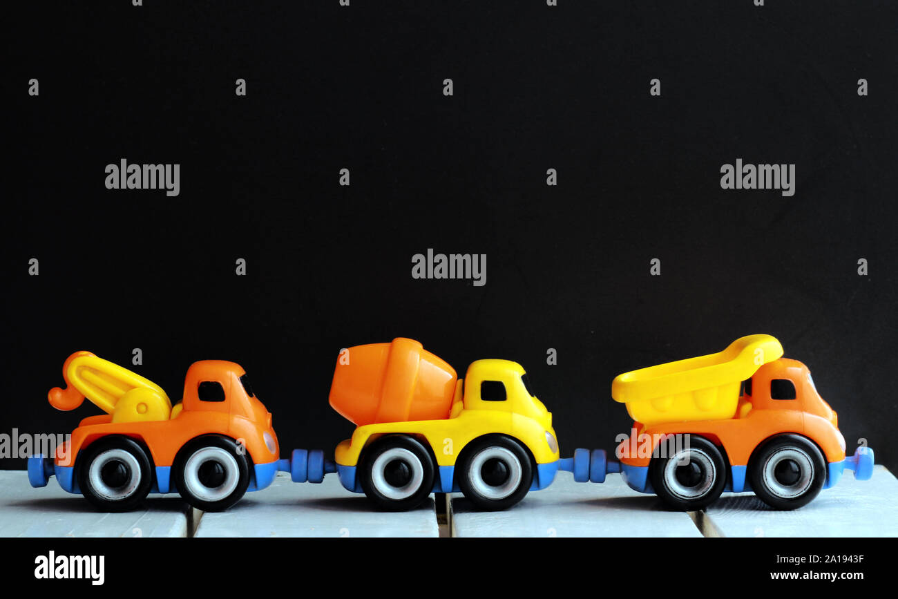 Linie von drei Spielzeug Lkw über schwarzen Hintergrund Stockfoto