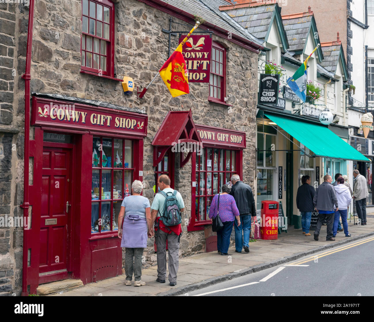 Fußgänger in Windows der Souvenirladen und Fisch und Chip Shop, Castle Street, Conwy oder Conway, Conwy County, Wales, Vereinigtes Königreich. Stockfoto