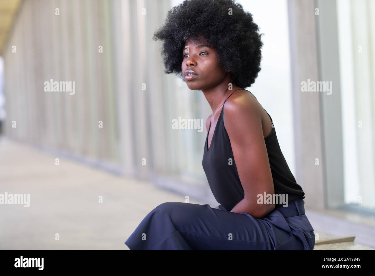 Hübsche junge afrikanische Frau in den Straßen der Stadt, auf der Bank sitzen Stockfoto