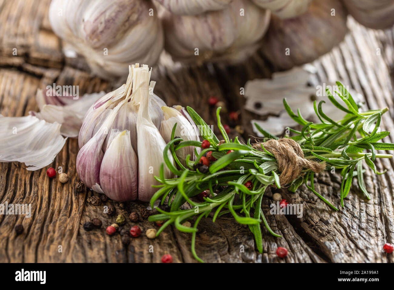 Knoblauchzehen Zwiebel mit frischem Rosmarin und Gewürzen auf alten Holztisch Stockfoto