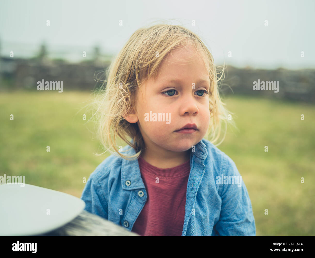 Ein kleines Kind beim Picknick Tisch draußen sitzen am Meer an einem nebligen Tag Stockfoto