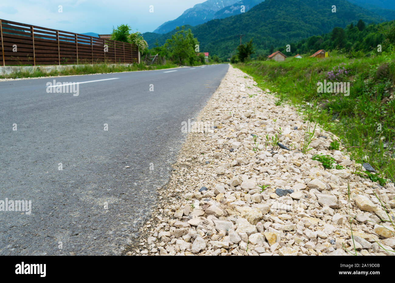 Asphaltierte Straße mit Kies auf der Seite führen zu den Bergen im Hintergrund Stockfoto