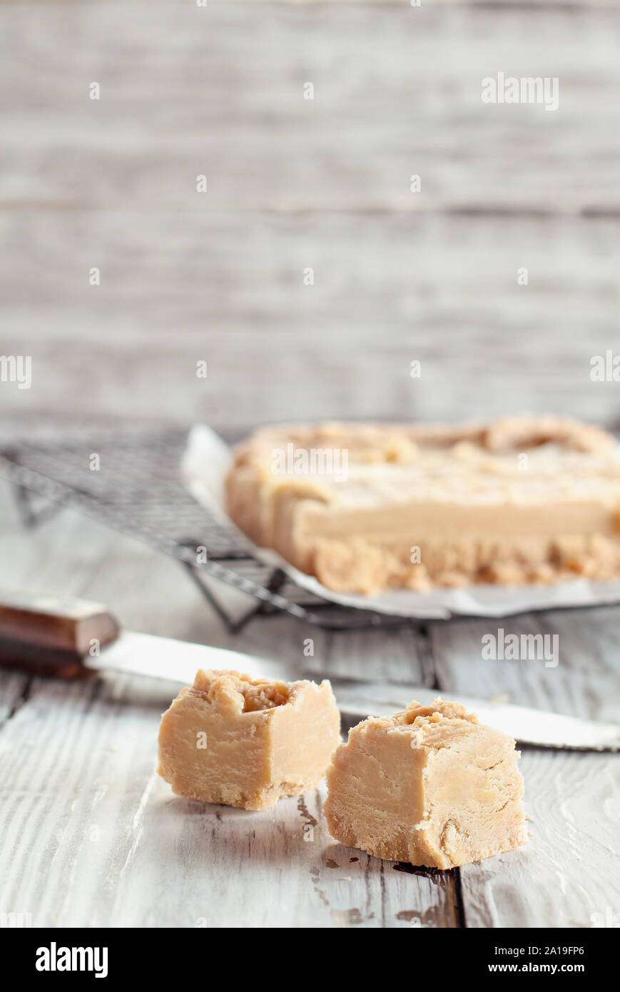 Plätze von köstlichen, hausgemachten Erdnussbutter fudge über einen rustikalen Holztisch. Selektiver Fokus auf Süßigkeiten in den Vordergrund mit verschwommenen Hintergrund. Stockfoto