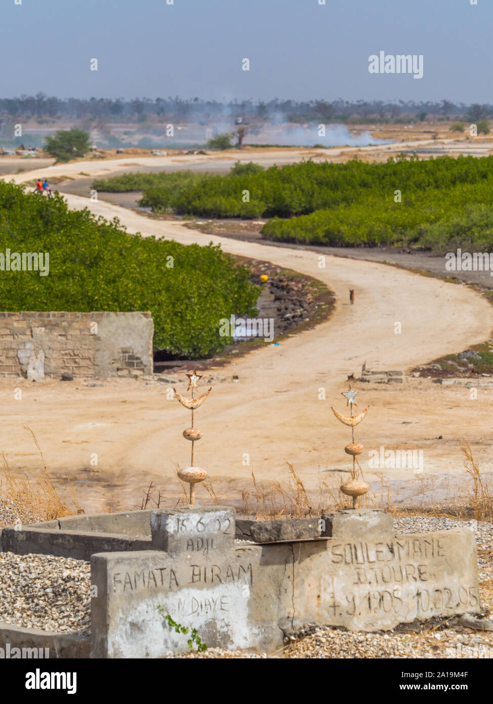 Joal-Fadiout, Senegal - Januar, 26, 2019: muslimische Gräber auf dem Friedhof. Eine kurvenreiche Straße im Hintergrund Joal-Fadiouth townl. Afrika. Stockfoto