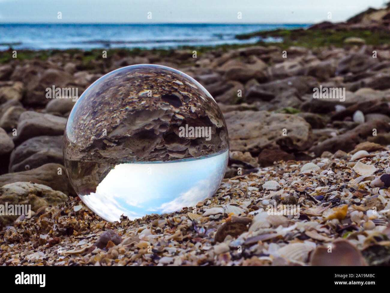 Glas Kristall Kugel Linse liegt auf dem Sand der Küste Landschaft Stockfoto