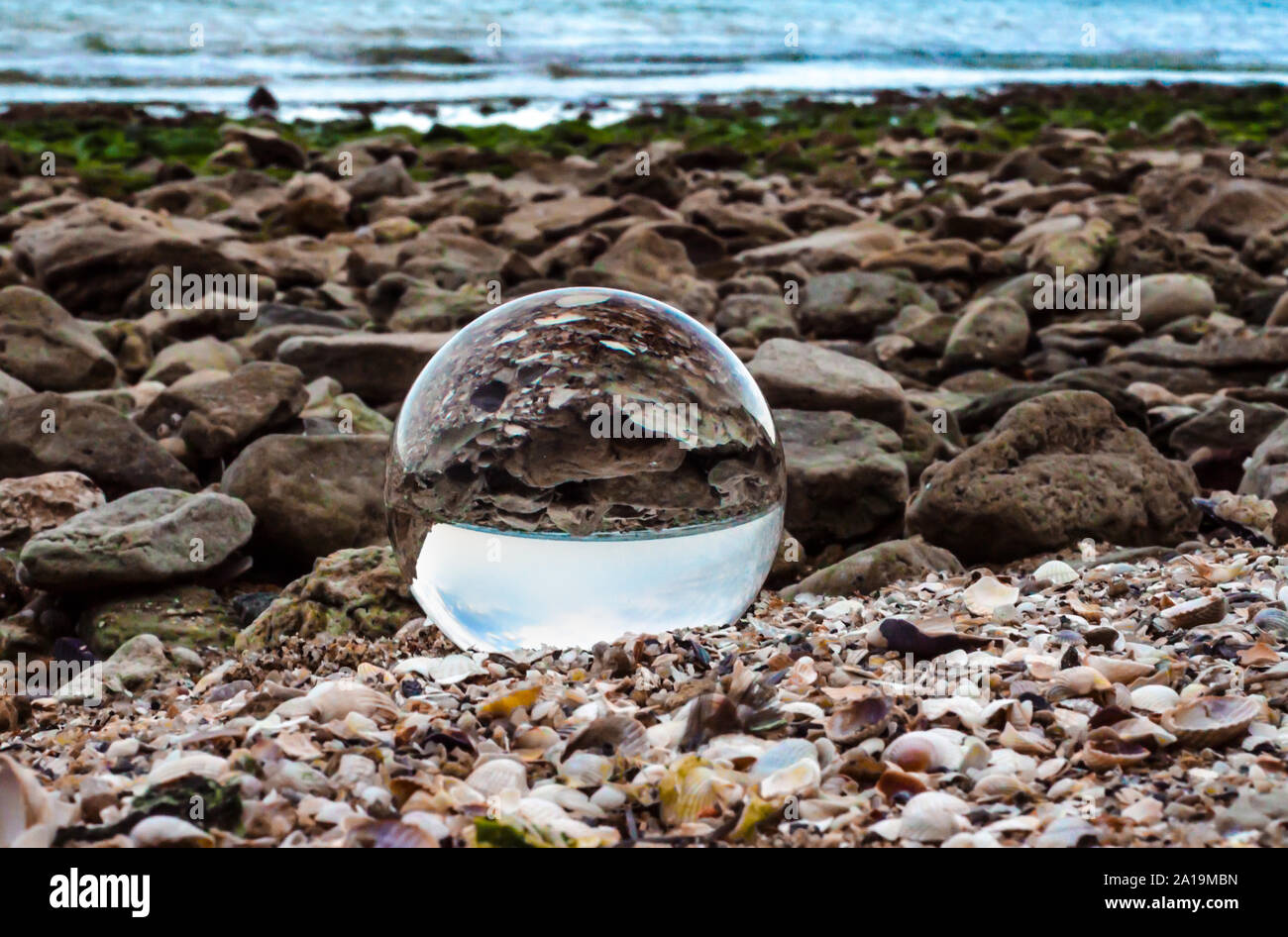 Glas Kristall Kugel Linse liegt auf den Sand am Meer Stockfoto