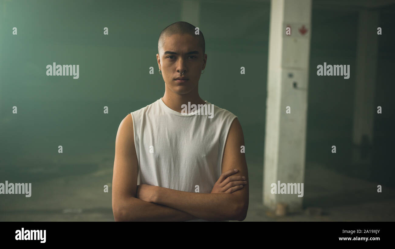 Protrait eines jungen Mannes mit Piercing auf beiden Ohren und Nase, intensiv in die Kamera schaut Stockfoto