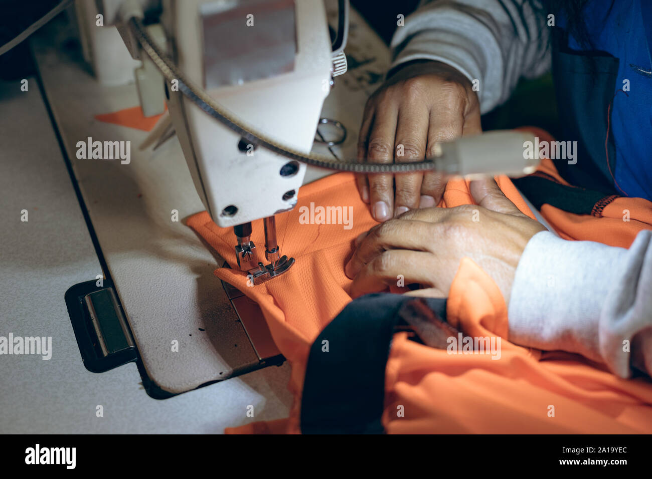 Die Hände einer Frau mit einer Nähmaschine in einer Fabrik Stockfoto