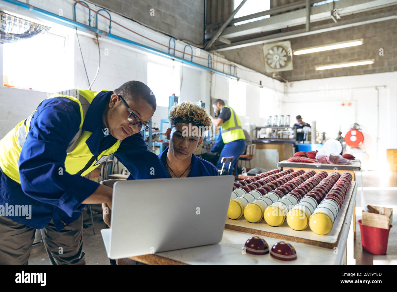 Junge Männer mit einem Laptop in einem sportgeräte Factory Stockfoto