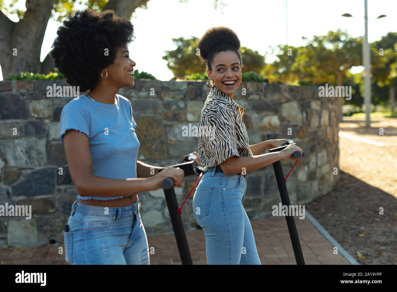 Zwei junge Frauen reiten e Scooter Stockfoto