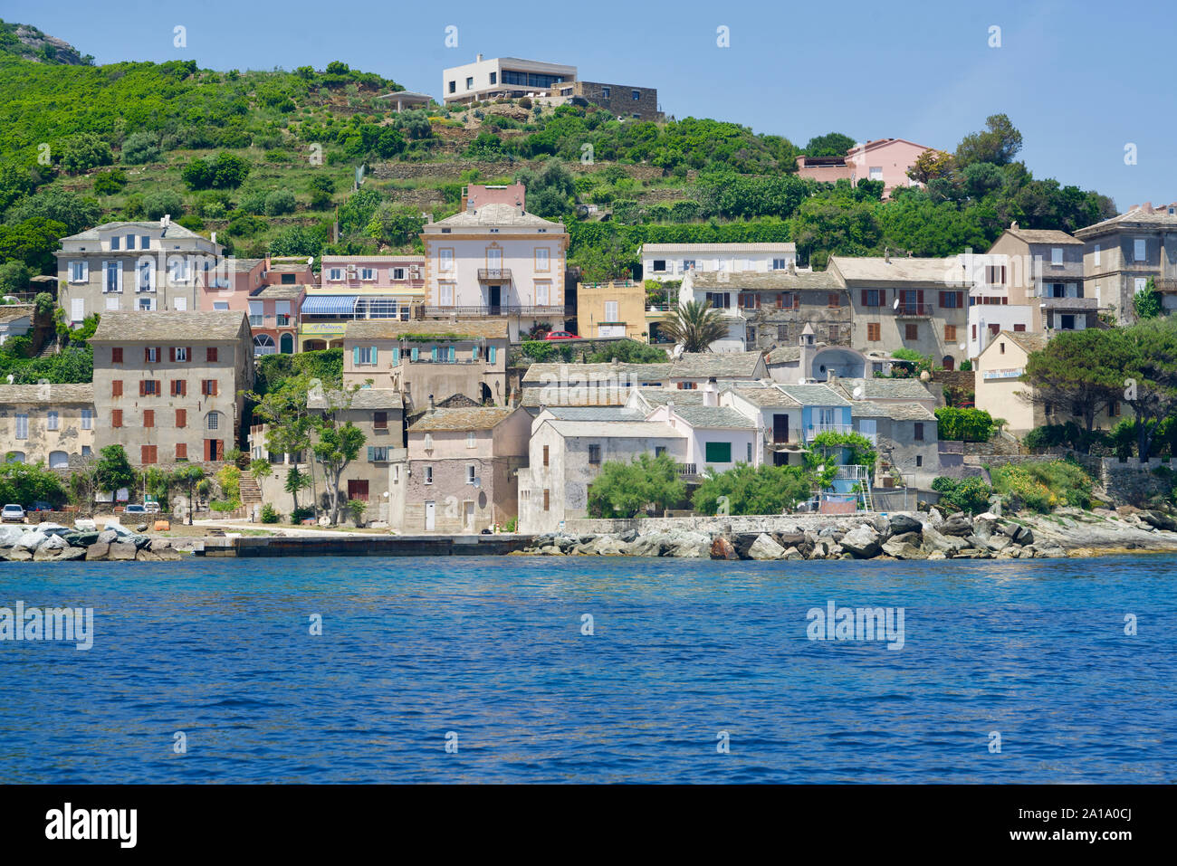 Korsische Häuser auf einem begrünten Felsen in das blaue Meer Stockfoto