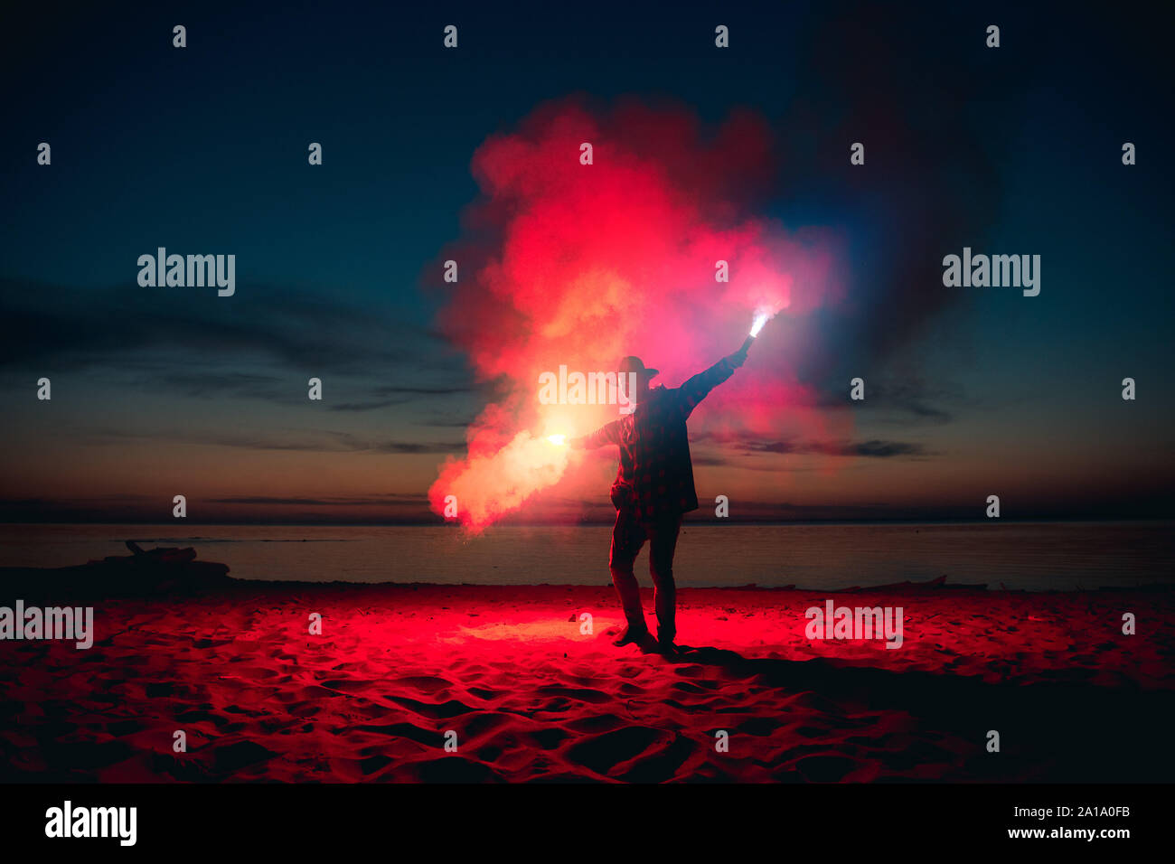 Man sendet Signal mit bunten Feuer und Feuerwerk in die Hände am sunset beach Stockfoto