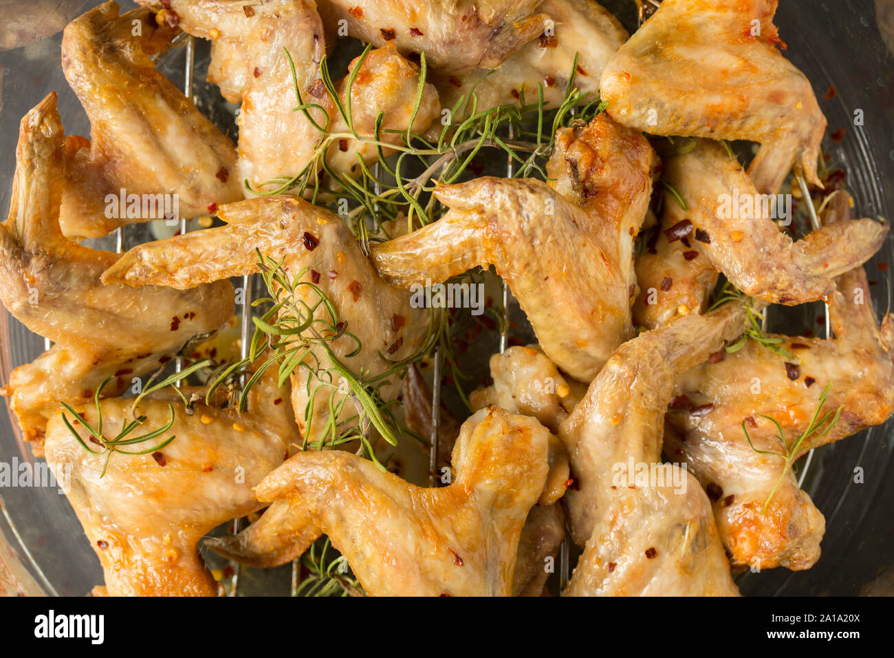 Gegrillte britischen Chicken Wings gekauft von einem Supermarkt in Großbritannien, die mit Chili Flocken und Rosmarin bestreut worden und serviert mit in Scheiben geschnittenen Lemo Stockfoto