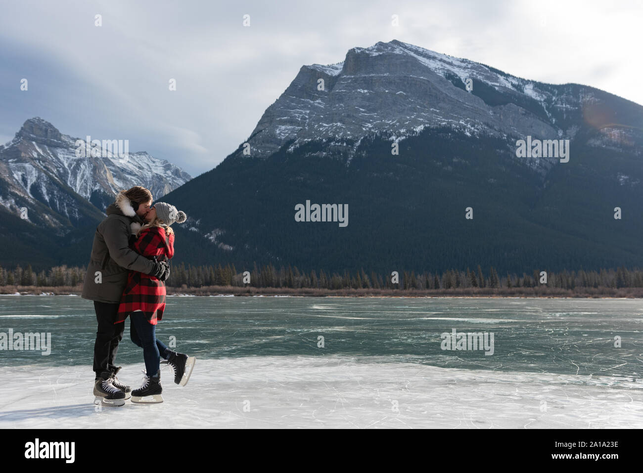 Glückliches Paar küssen einander in verschneiter Landschaft Stockfoto