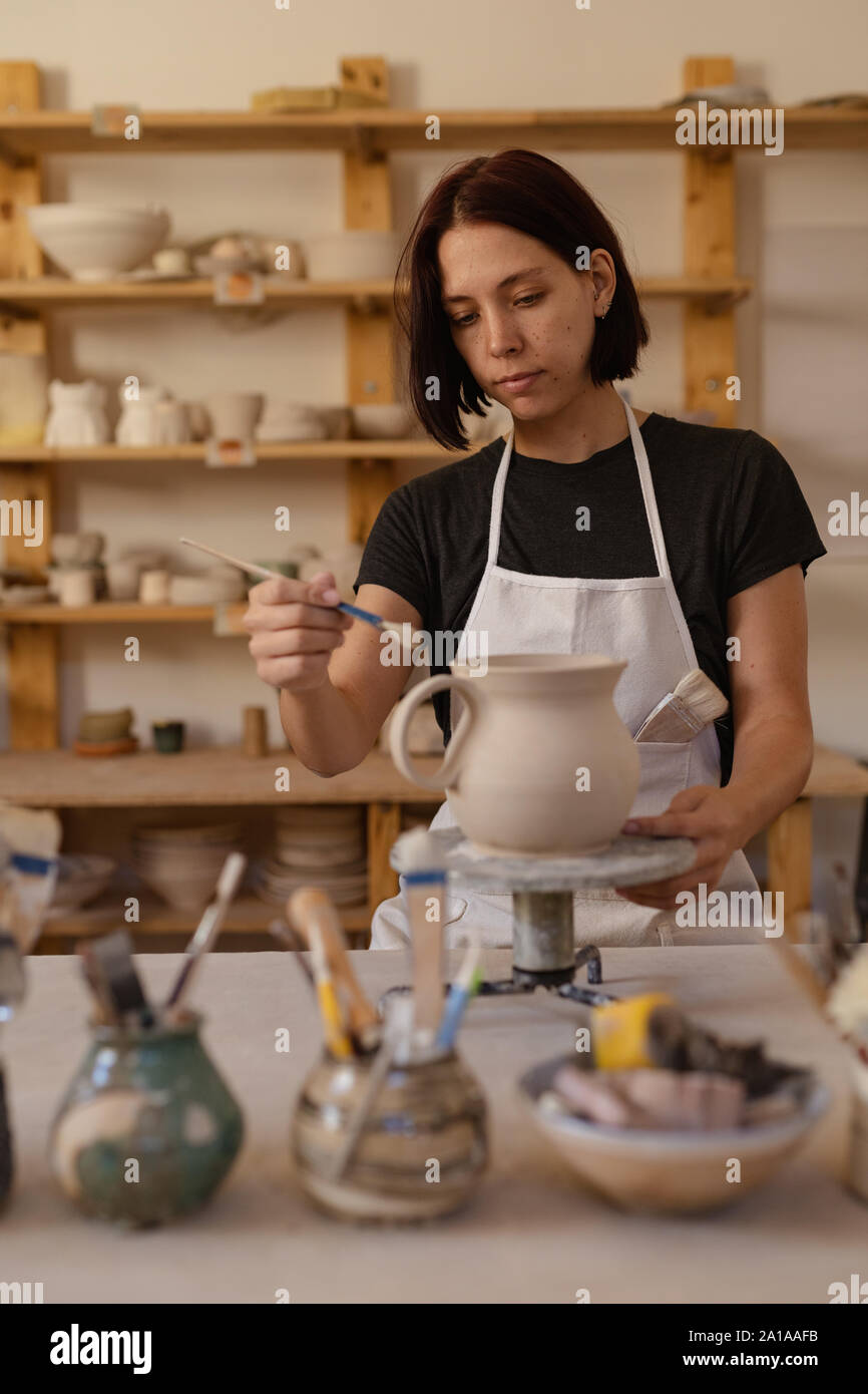 Weibliche Potter in einer Töpferwerkstatt Verglasung eine Kanne Stockfoto