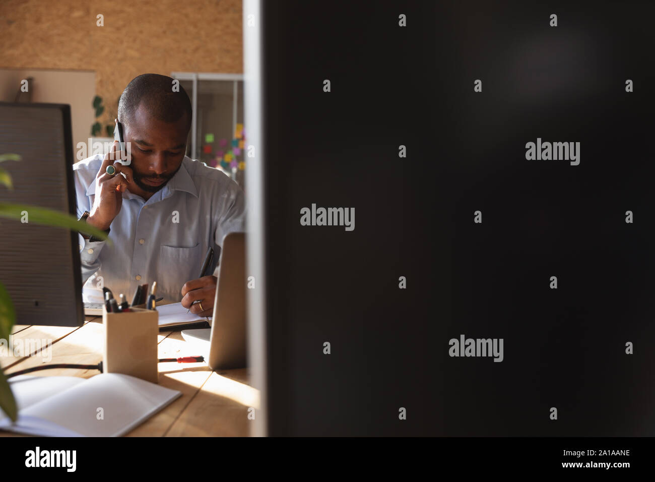 Young Creative Professional Mann am Telefon in einer sonnenbeschienenen Büro Stockfoto