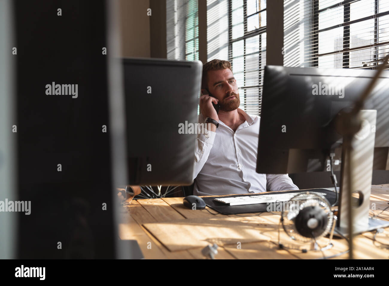 Young Creative Professional Mann am Telefon in einer sonnenbeschienenen Büro Stockfoto
