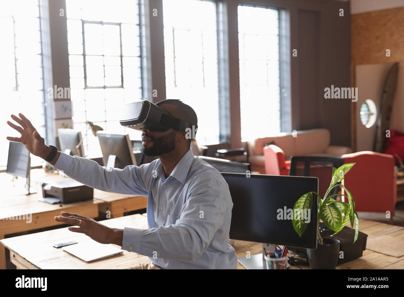 Junge kreative Professionelle man mit VR-Headset in einem sonnendurchfluteten Büro Stockfoto