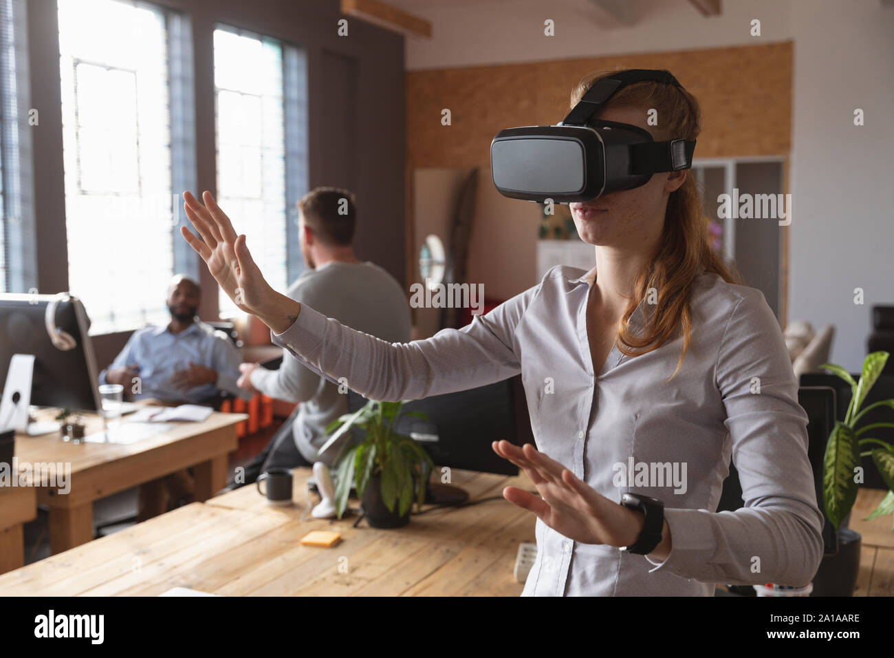 Young Creative Professional Frau mit VR-Headset in einem sonnendurchfluteten Büro Stockfoto