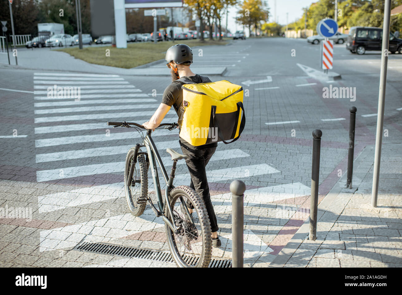 Männliche Kurier zu Fuß mit dem Fahrrad auf die Stadt Straße, Lieferung von Nahrung mit thermischen Rucksack. Essen Konzept Stockfoto