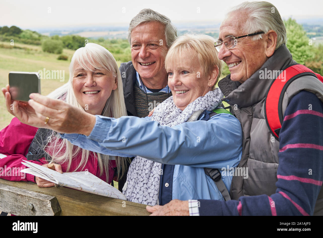 Gruppe von älteren Freunden Wandern in der Landschaft stehend durch Tor und unter Selfie auf Handy Stockfoto