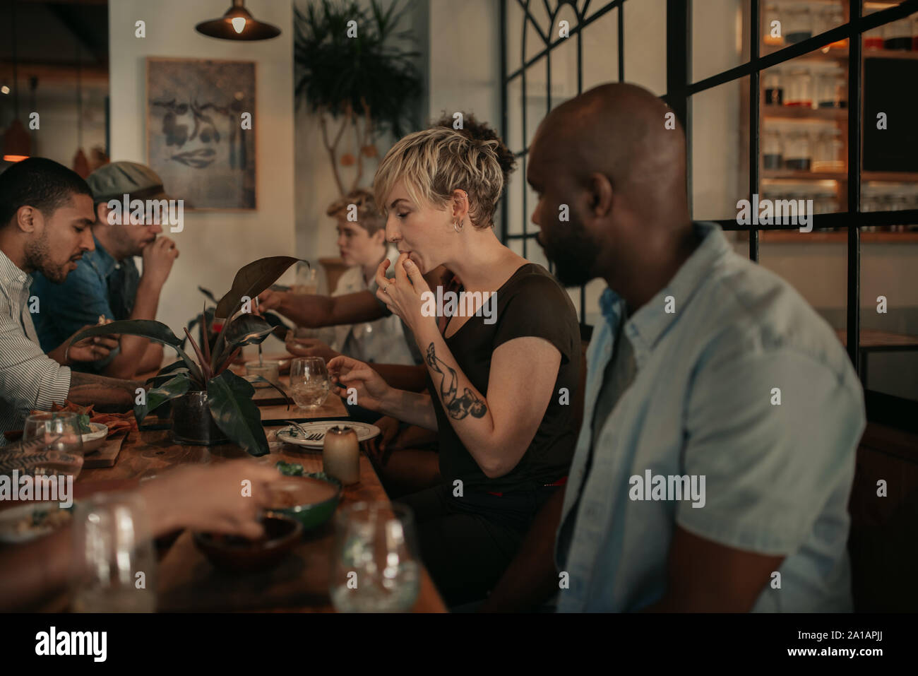 Diverse junge Freunde genießen ein Bistro Mahlzeit am Abend Stockfoto