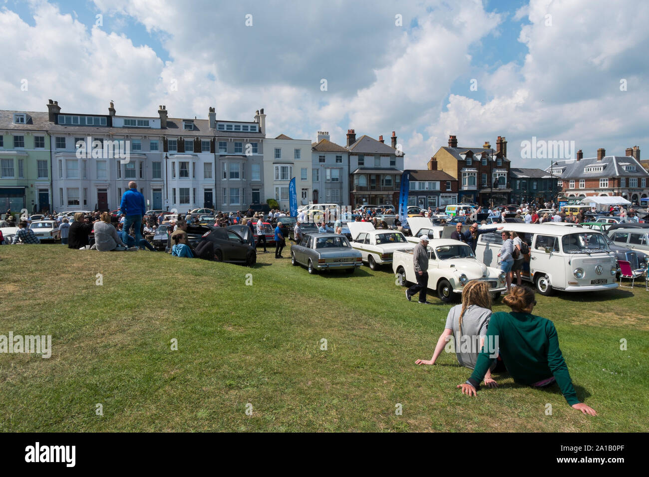 Ein paar sitzt auf dem Gras genießen der Deal Classic Motor Show auf Walmer Grün durch den Strand, Deal, Kent, Großbritannien Stockfoto