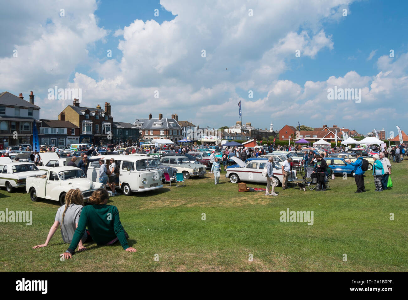 Ein paar sitzt auf dem Gras genießen der Deal Classic Motor Show auf Walmer Grün durch den Strand, Deal, Kent, Großbritannien Stockfoto