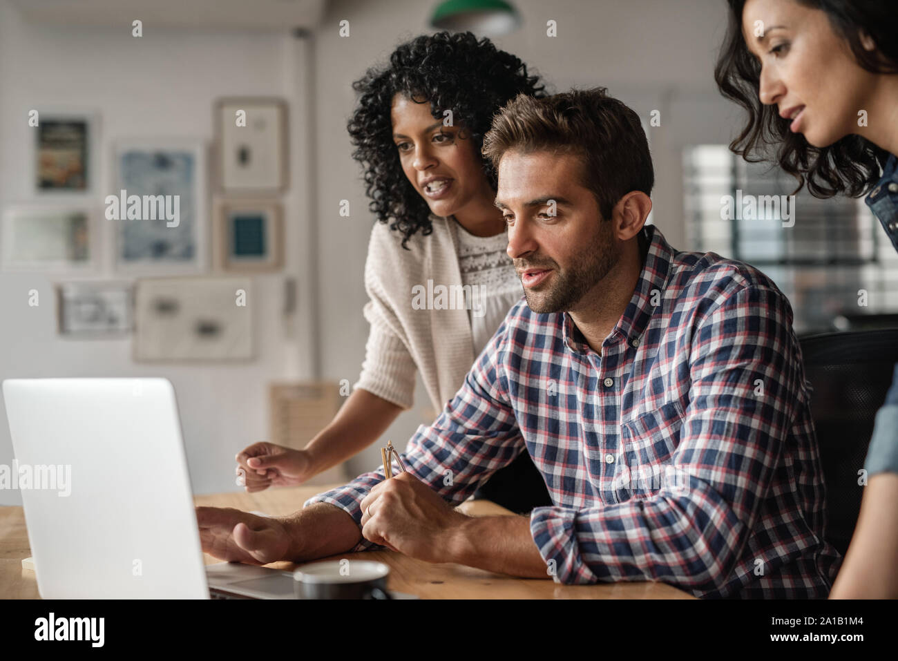 Drei verschiedene Designer mit einem Laptop zusammen bei der Arbeit Stockfoto