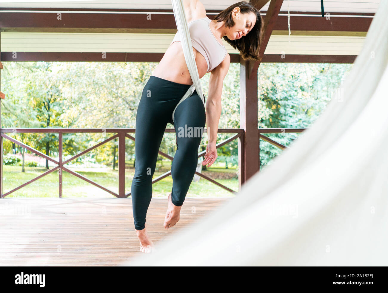 Passen hübsche junge Frau anti-gravity Fliege Yoga in weiß Hängematte im Freien. Stretching Übungen im Fitness Training im Park oder Garten. Sport- und er Stockfoto