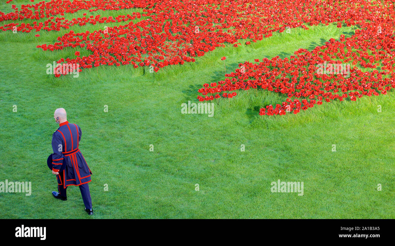 Beefeater zu Fuß durch die Kunst der Installation Blut fegte Länder und Meere von Rot am Tower von London. Stockfoto