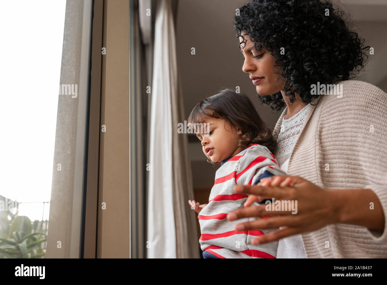 Mutter und Tochter durch ein Fenster zu hause suchen Stockfoto