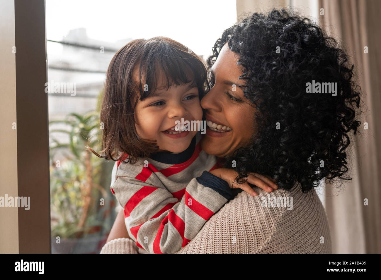 Liebevolle Mutter ihrer kleinen Tochter zu Hause umarmen Stockfoto