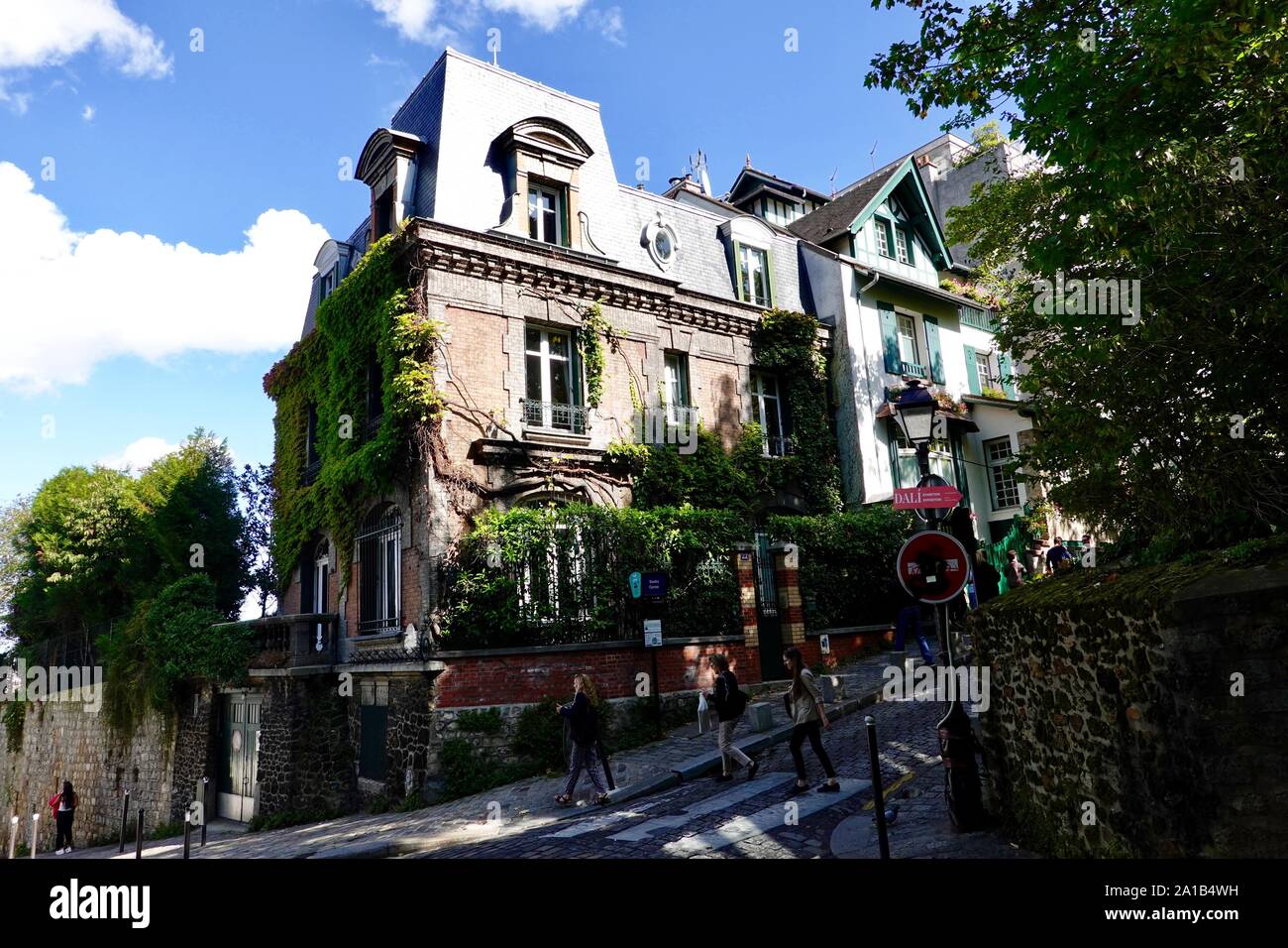 Menschen gehen auf der steilen Straße, vorbei an der Bushaltestelle Saules-Cortot im Norden von Montmartre, Paris, Frankreich Stockfoto