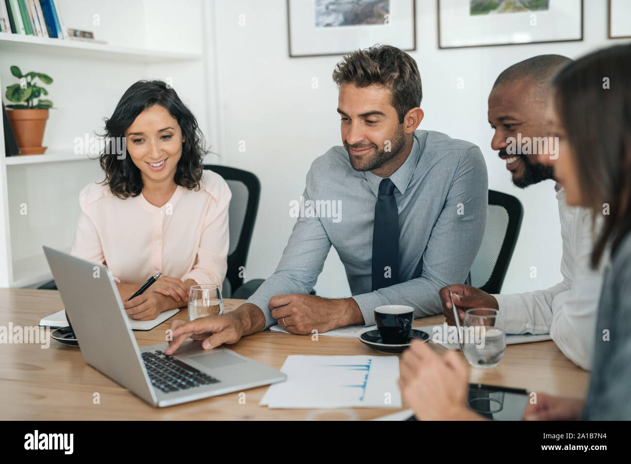 Lächelnd Geschäftsleute auf einem Laptop arbeiten zusammen in einem Büro Stockfoto