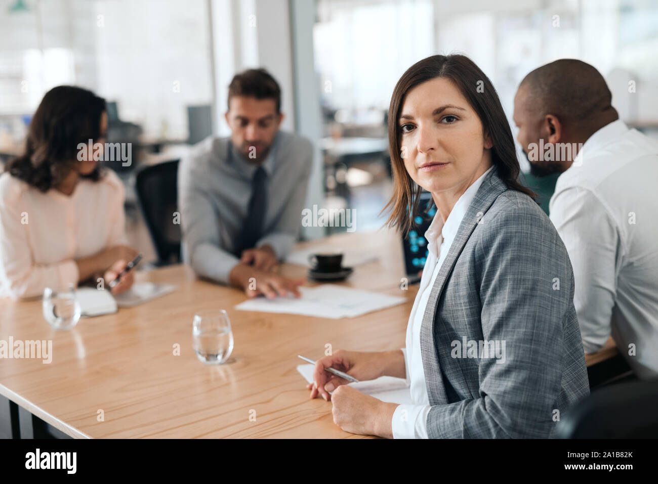 Fokussierte Geschäftsfrau, Sitzen mit Kollegen während einer Konferenz Stockfoto