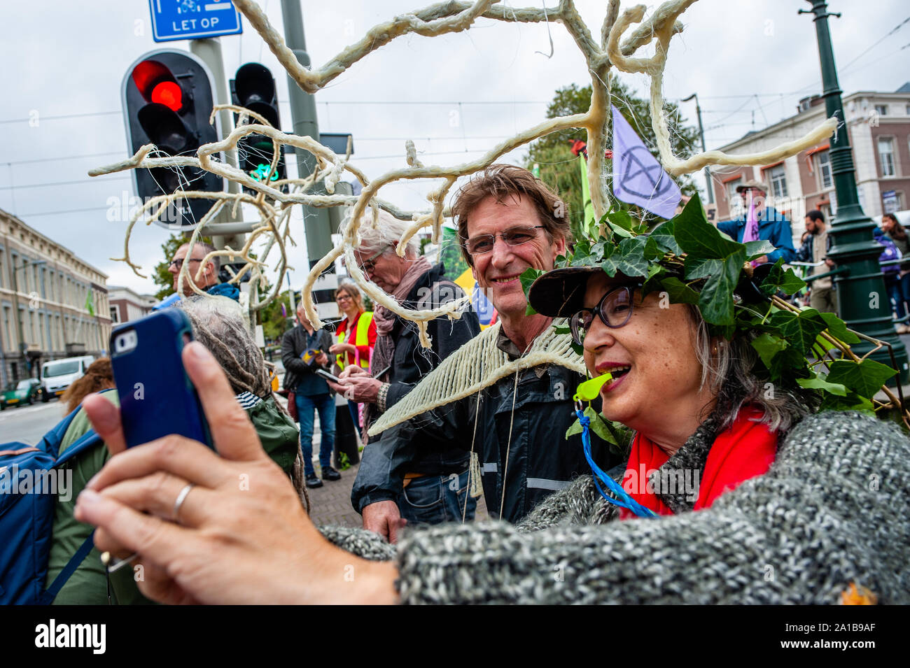Eine Frau tragen fake Blätter auf den Kopf nimmt eine selfie mit einem Mann  während der Demonstration. Nach Arnhem - Künstler, Rob Voerman eine  Petition eröffnete die Amazon zu speichern und Bolsonaro,