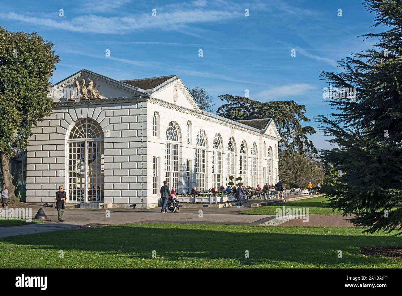 Die Menschen Essen und Trinken an den Tischen vor der Orangerie an der Royal Botanic Gardens, London, TW9 3AB (Kew) Stockfoto