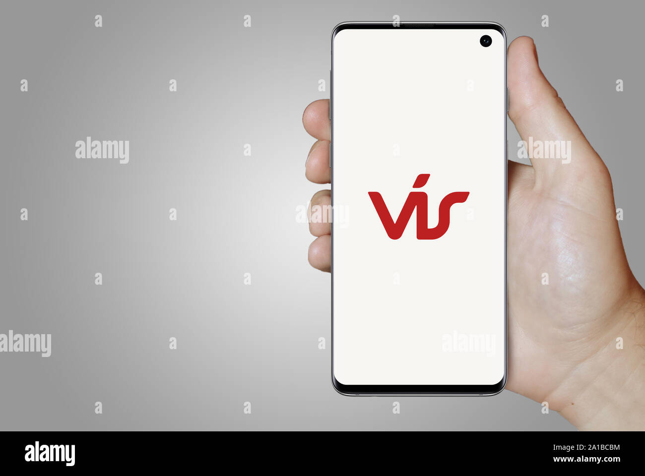 Ein Mann hält ein Smartphone mit dem Logo der Firma Vátryggingafélag Íslands auf Nasdaq Island aufgeführt. Grauen Farbverlauf Hintergrund. Credit: PIXDUCE Stockfoto