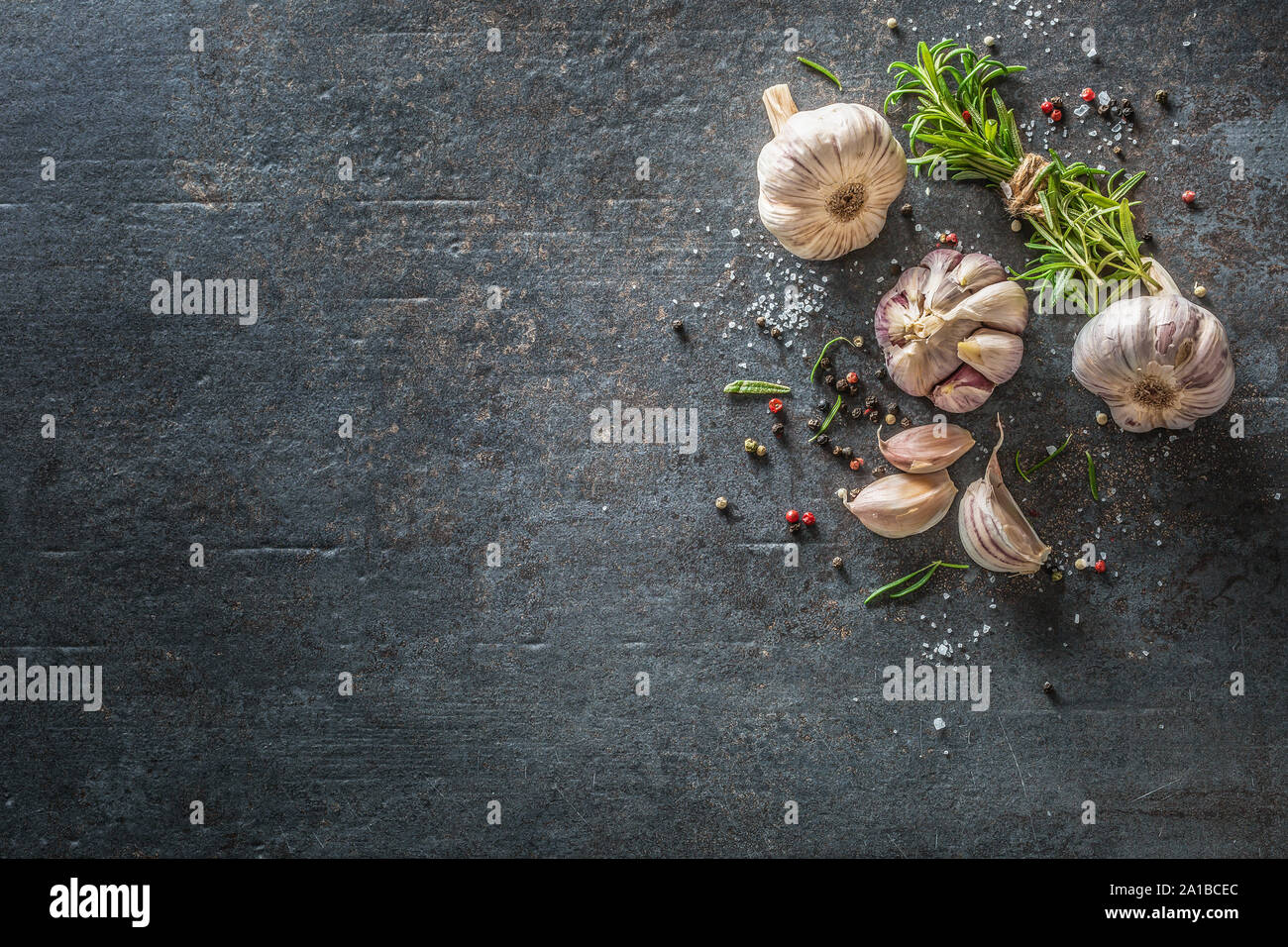 Knoblauchzehen und Zwiebel mit frischem Rosmarin Salz und Gewürz auf konkrete Tabelle Stockfoto
