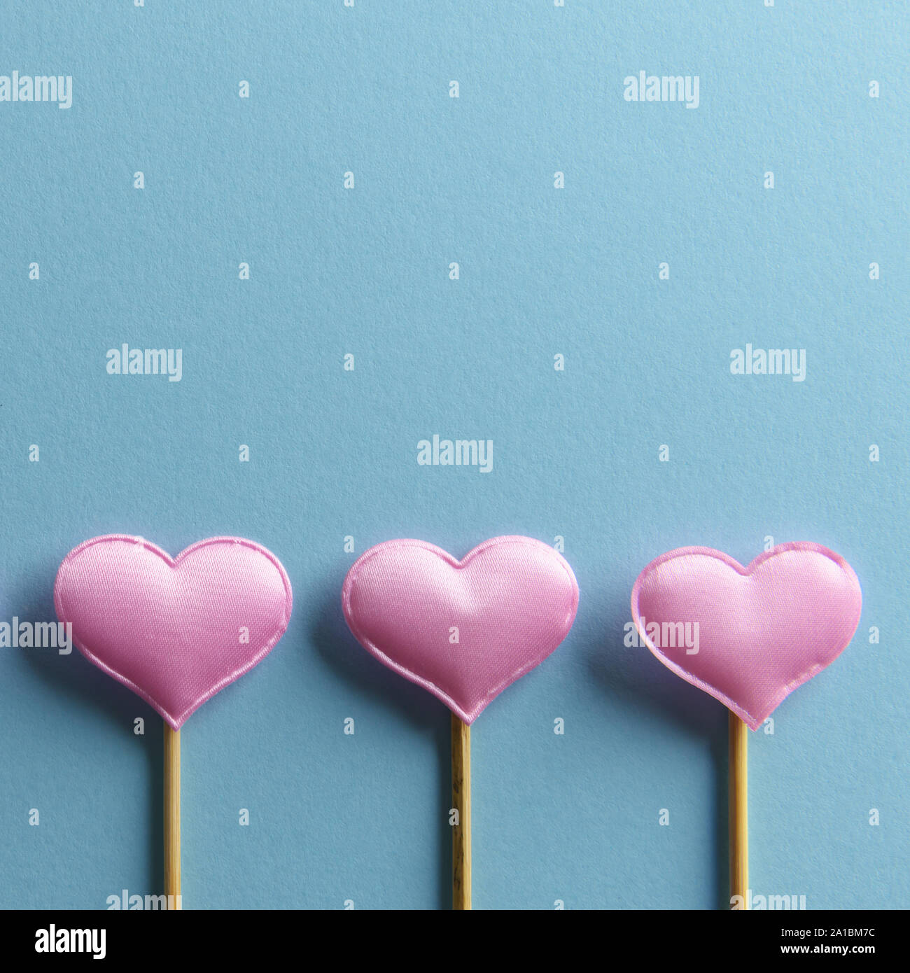 Drei rosafarbenen textile Herzen auf Holzstäbchen auf blauem Hintergrund. Valentines Tag Hintergrund, kreative Textur und liebe Konzept Stockfoto