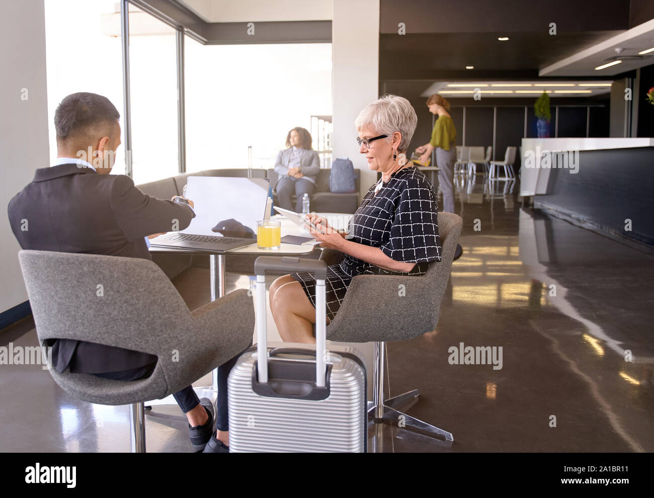 Lächelnd diverse Kollegen in der modernen Lounge im Flughafen sitzen mit Gepäck entwickeln Geschäftsideen zusammen Stockfoto