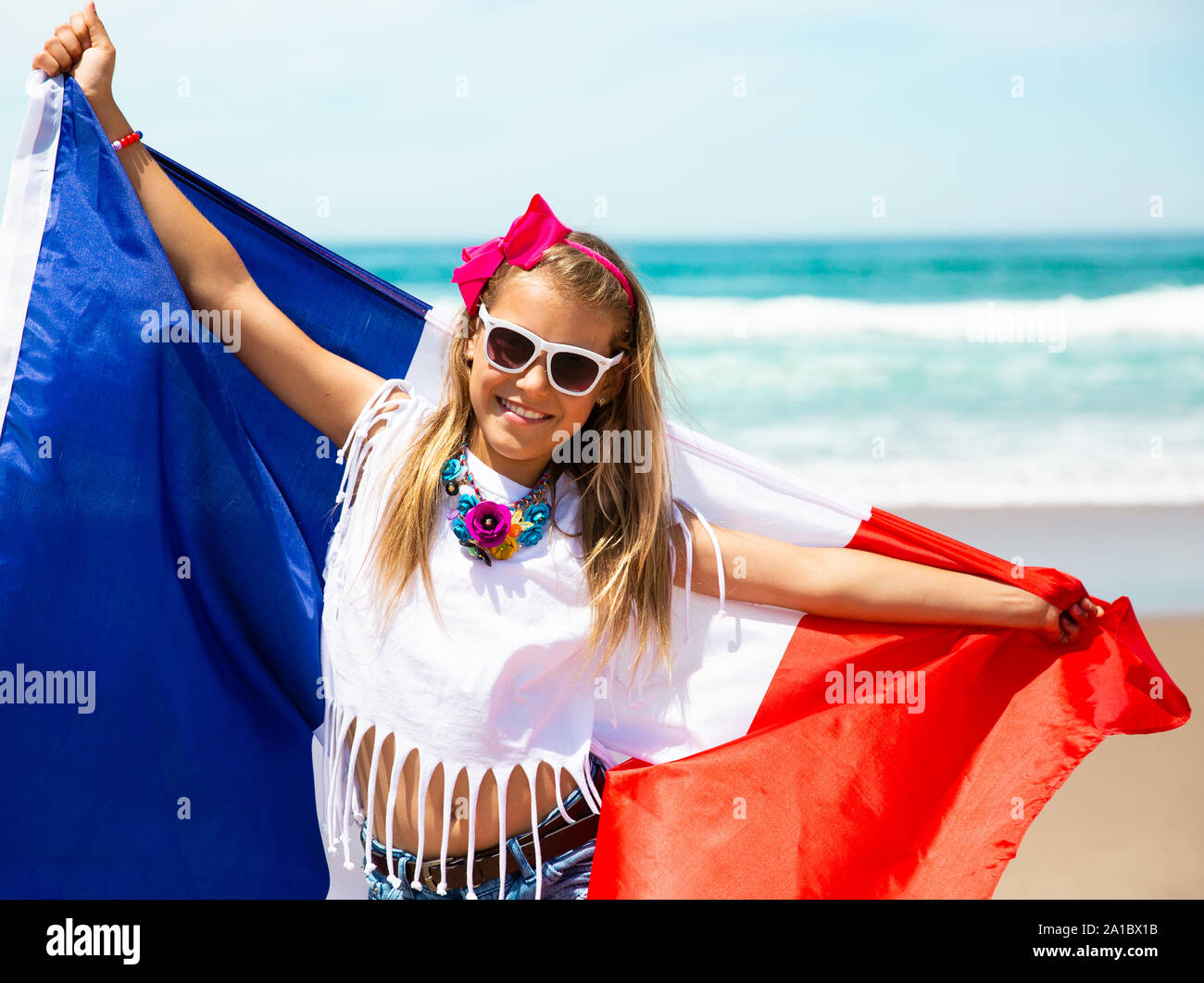 Gerne französische Mädchen trägt flattern Blau Weiß Rot französische Flagge Frankreichs gegen den blauen Himmel und den Atlantik Hintergrund Stockfoto