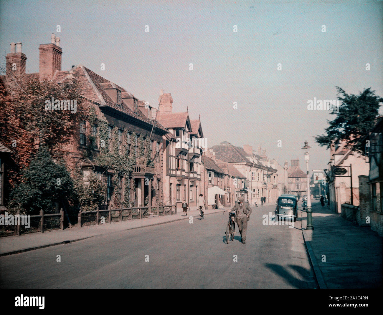 Vintage Farbfoto, 1939, zeigen die Hohe Straße in Stratford-upon-Avon, Warwickshire, England. Ein Mann schiebt sein Fahrrad in der Mitte der Straße. Stockfoto