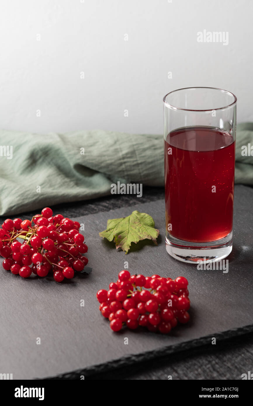 Rote Saft von viburnum in einem Glas auf einem hellen Hintergrund. In der Nähe von viburnum Beeren, und Leinen. Gesunde Ernährung Stockfoto